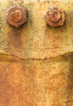 Close-up of rusted metal with bolts in a junkyard setting