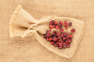Dried cranberries on jute cloth, top view, macro.