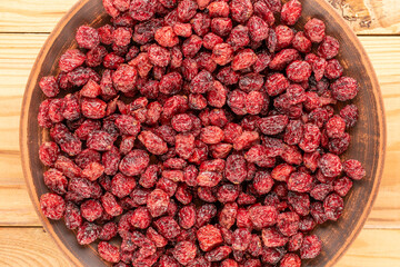 Dried cranberries with ceramic dishes on a wooden table and top view, macro.