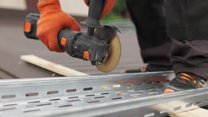 Man works circular saw. Sparks fly from hot metal. Man hard worked over the steel. Male hand cuts off pieces of pipe with angle grinder. Cutting of a steel with splashes of sparks at construction site