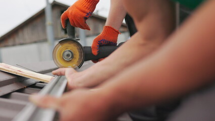 Male hand cuts off pieces of pipe with angle grinder. Cutting of a steel with splashes of sparks at construction site. Slow motion of construction worker cutting steel beam. A man cuts a metal profile