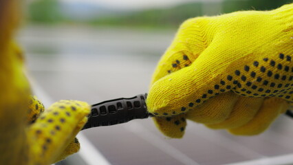 Solar Station Equipment. Connecting wires of solar panels at a solar farm. Engineers connect electrical system outdoors on a background of solar panels. Worker in protective gloves connects wire.