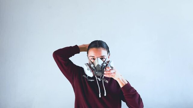 A young attractive girl puts a gas mask on her head and shows how to use it correctly.