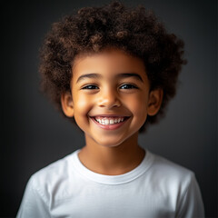 A cheerful curly-haired child in a white shirt smiling brilliantly.