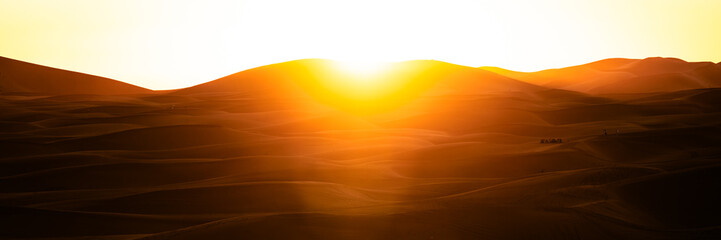 Sand dunes desert landscape at sunset, with camel  and quadbike tours.  Erg Chebbi. Merzouga. Sahara desert. Morocco. Africa.