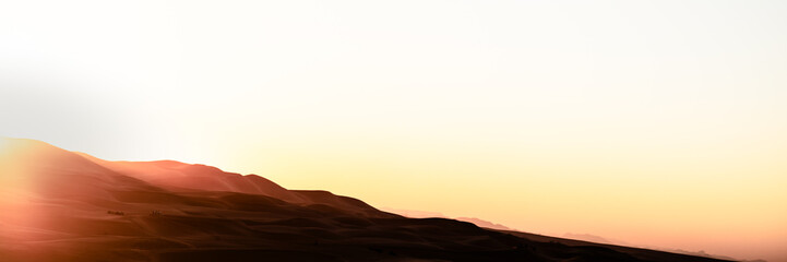 Fototapeta premium Sand dunes desert landscape at sunset, with camel tour. Erg Chebbi. Merzouga. Sahara. Morocco. Africa.