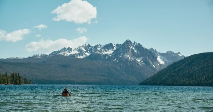 A canoe paddles across a mountain lake