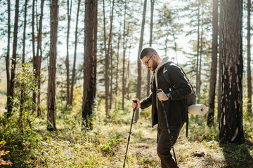 Young caucasian man hiking or trekking through the forest	
