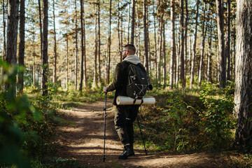 Fototapeta premium Young caucasian man hiking or trekking through the forest 