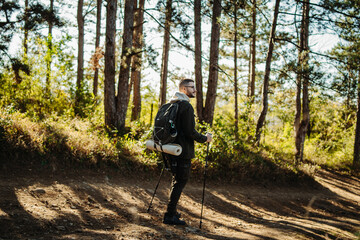 Young caucasian man hiking or trekking through the forest	