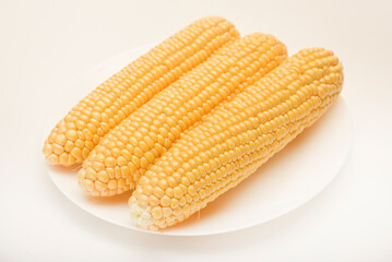 Ripe corn cobs on a white plate. Ripe vegetables.