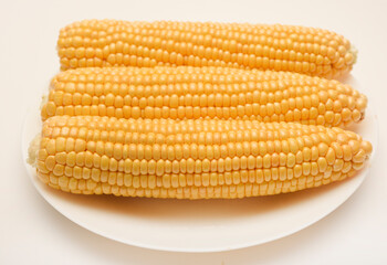 Ripe corn cobs on a white plate. Ripe vegetables.