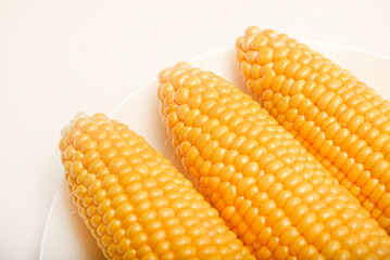 Ripe corn cobs on a white plate. Ripe vegetables.