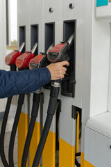 A person refuels their vehicle at a gas station, selecting the EuroDiesel nozzle. The scene...