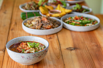 Khao Soi Chiang Tung is served in a bowl with sticky rice noodles and a flavorful soup that is Chiang Tung style. The delicious Khao Soi Chiang Tung is a popular noodle dish among Tai Yai people.