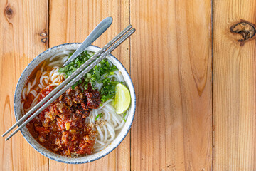 Khao Soi Chiang Tung is served in a bowl with sticky rice noodles and a flavorful soup that is Chiang Tung style. The delicious Khao Soi Chiang Tung is a popular noodle dish among Tai Yai people.