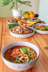Khao Soi Chiang Tung is served in a bowl with sticky rice noodles and a flavorful soup that is Chiang Tung style. The delicious Khao Soi Chiang Tung is a popular noodle dish among Tai Yai people.