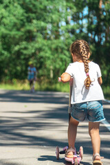 Little girl riding scooter. Kids ride kick board. Child playing on suburban street on sunny summer...
