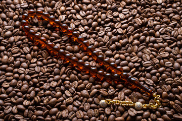Squeezing Ottoman Turkish Amber Rosary , macro detail shot on coffee beans