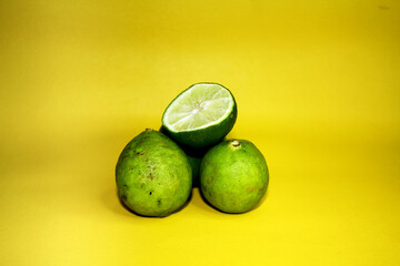 Lime with 3 whole fruits and one that has been cut in half.	