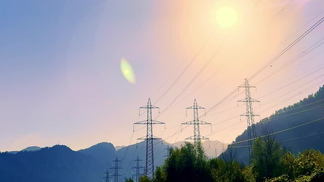 Electricity Pylon with Mountain View and Against Sun with Lens Flare and Trees in the Swiss Alps in a Mountain Valley in a Sunny Day with Blue Clear Sky in Flums, St. Gallen, Switzerland.