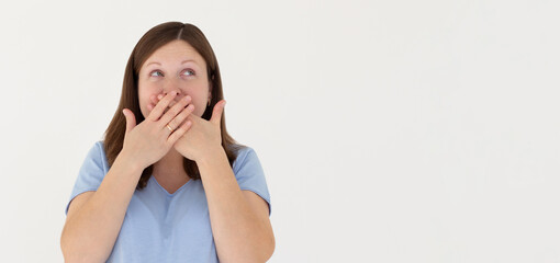 Portrait of a shocked young girl in blue t-shirt looking aside with mouth covered isolated over white background