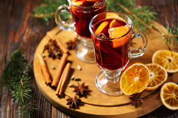 Hot mulled wine or alcohol grog with oranges and spices of cinnamon in a glasses on wooden table. A...