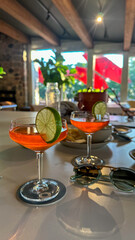 vibrant pink cocktails with lime garnish in coupe glasses, complemented by stylish sunglasses in a bar