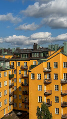 Colorful yellow apartment buildings in Stockholm Sweden with windows, balconies and vibrant blue sky above