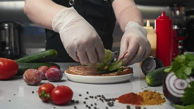In restaurant's kitchen, chef decorates toasted sandwich bread with leaves of juicy green salad made from variety of herbs and plants. Bread for bruschetta is generously poured with sauce, and around