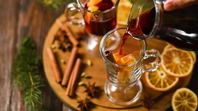 Hot mulled wine or grog with oranges and spices of cinnamon in a glasses on wooden table. A traditional warming drink for the autumn winter season.