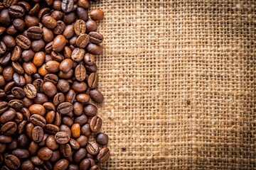 Fototapeta premium Coffee bean on rustic jute fabric and wooden background, wide angle shot