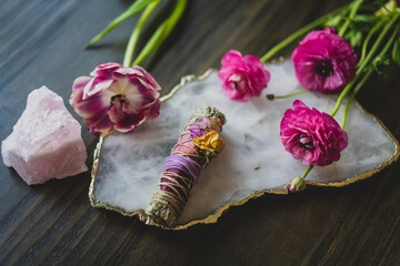 sage smudge stick with pink flowers and crystals