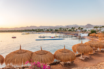 Straw umbrellas on empty beach. Beautiful empty beach with sun umbrellas and sunbeds