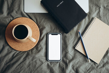 Bible, phone, laptop and cup of coffee on a grey bed background, copy space.