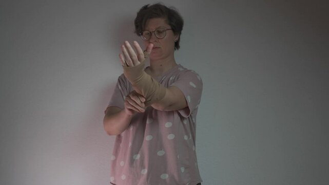 Woman puts on compression sleeve for vein health on her arm, aiding in thrombosis and embolism prevention. This medical garment supports circulation and helps manage varicose veins and venous issues. 