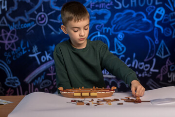Focused young boy assembling a wooden ship model at a desk, surrounded by detailed instructions,...