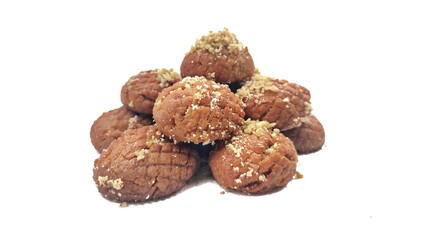 Photo of a pile of Greek melomakarona, traditional honey-soaked Christmas desserts topped with crushed walnuts, isolated against a white background.