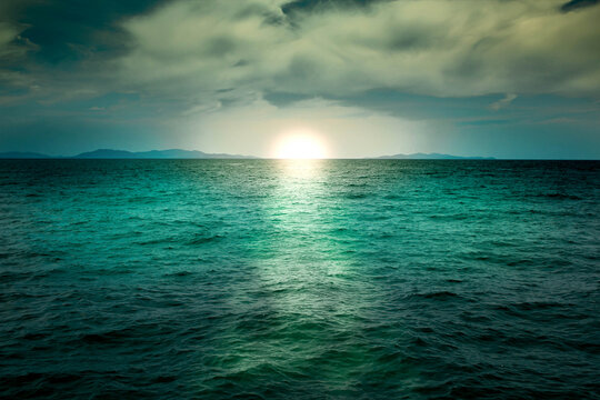 Emerald green sea with sun and cloudy sky background, calm ocean water surface, relaxing sunset or sunrise morning atmosphere, dark natural texture reflection.