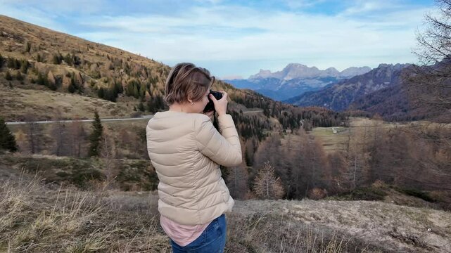 A Caucasian woman photographs scenic Dolomiti National Park in autumn, perfect for nature and travel themes