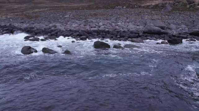 A drone flight capturing the waves as they crash onto the beach in Norway 
