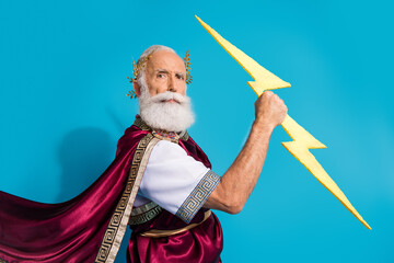 Photo of handsome senior male hold strike thunder lightning wear ancient greek god king dress isolated on blue color background