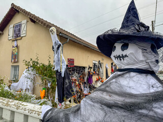 Naklejka premium Halloween decorations adorn a house in a suburban neighborhood, showcasing ghosts, spiders, and a scarecrow in early October
