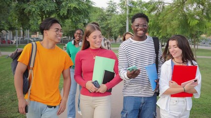 Diverse group of students waling, talking and smiling outdoors, young friends holding notebooks and backpacks, socializing and enjoying conversation, multicultural college teens standing at university