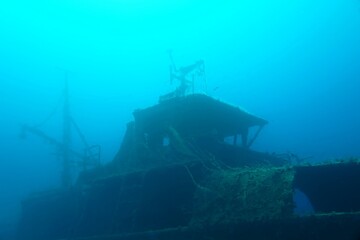 Dark silhouette of the ship wreck, deep sea. Travel photo, seascape with the sunken boat. Deep blue...