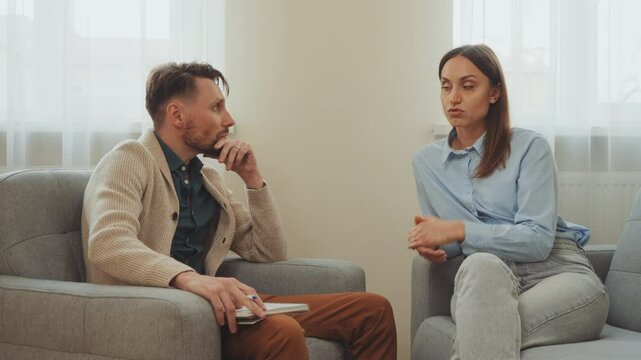 Psychologist attentively listens and takes notes as client shares concerns in calm office. Natural light adds sense of openness. Therapy session focuses on personal growth and emotional support