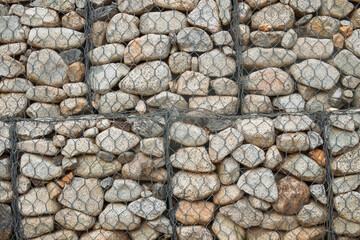 Gabion wall, landscape design. Gabion consists of a series of rectangular cells of wire mesh filled with irregularly shaped stones of different sizes and shades, environment.