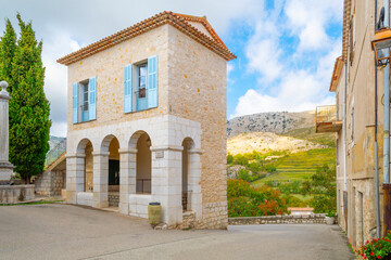 A picturesque, narrow building with arched doorway and stone windows along Rue Principale in the medieval hill town of Gourdon, France, in the Alpes-Maritimes region.