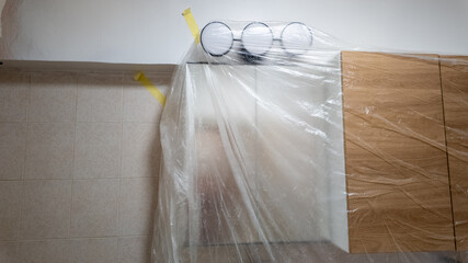 A kitchen undergoing renovation is protected with plastic sheeting, representing the concept of...