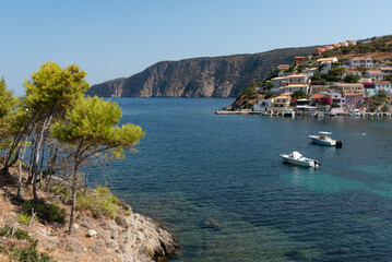 Fototapeta premium Assos village overlooking turquoise bay in kefalonia, greece, with pine trees framing the view